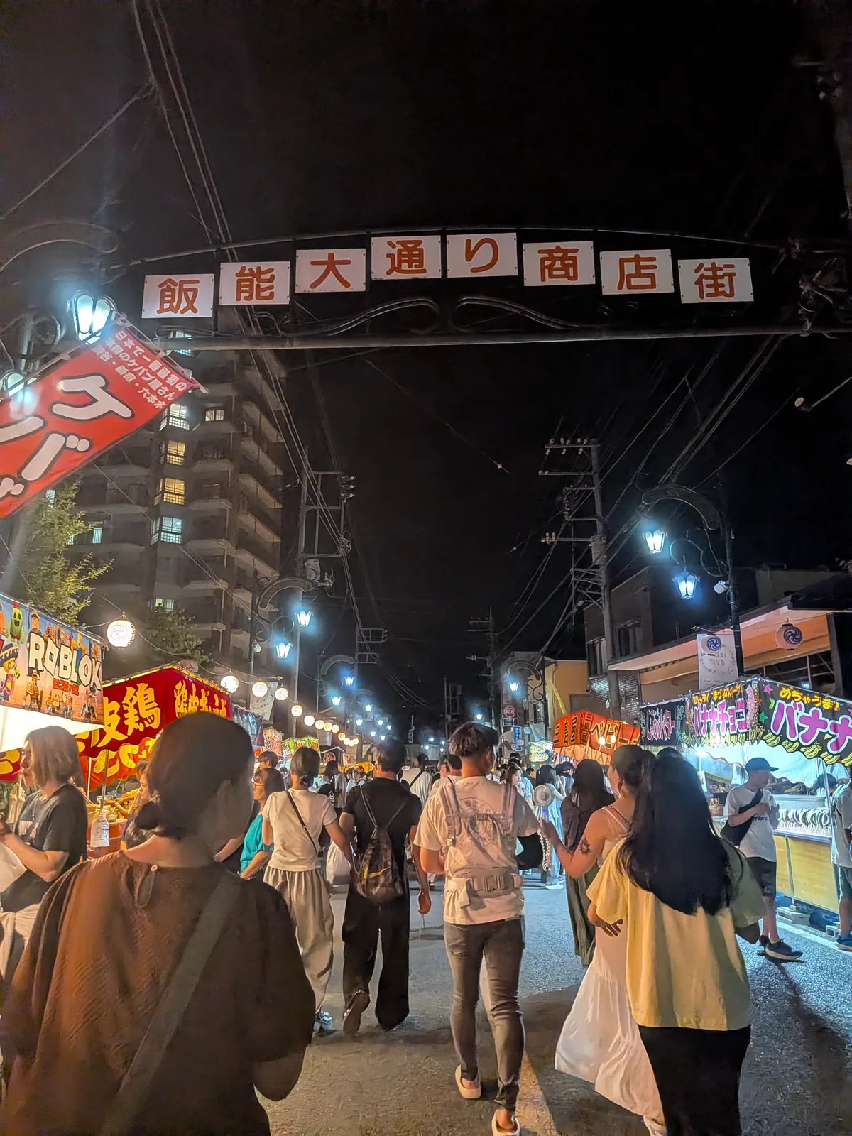 宵宮の出店と来場者でにぎわう飯能大通り商店街のアーチ下